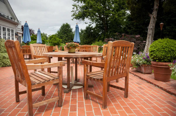 Tables and chairs made from teak on a brick patio.