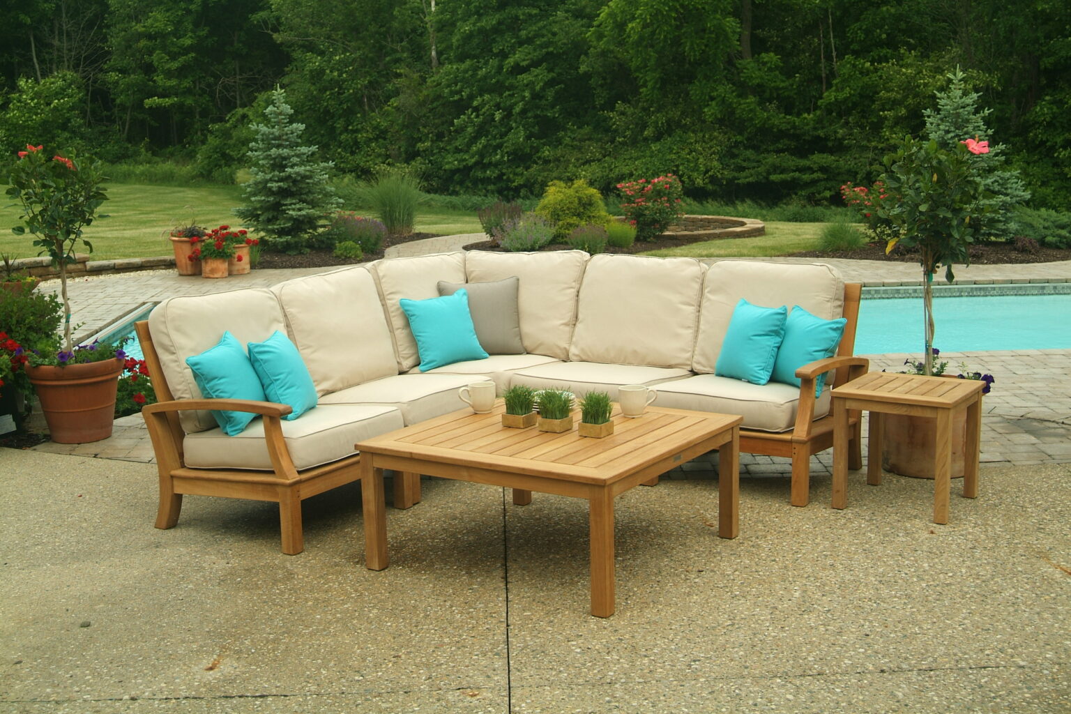 A TB Monterey outdoor sectional positioned by a pool with aqua blue coloured pillows