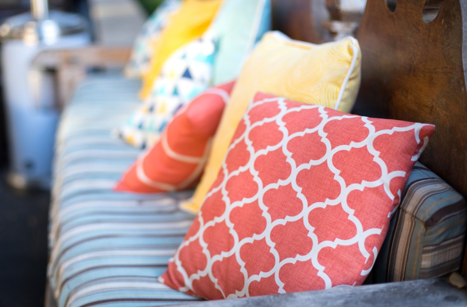 A close up of an orange and white outdoor cushion placed on patio furniture